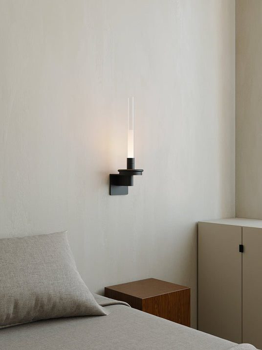 Lit beside a bed with a pale pillow, a timber nightstand and a tall cabinet