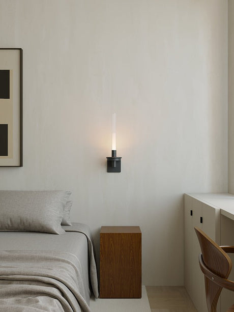 Lit in a bedroom between a framed print, a made bed and a small desk