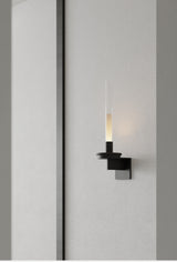 Lit warm in a corridor, the stem casting a soft pool down the gray wall