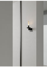 Lit on a gray corridor wall beside a tall dark panel running floor to ceiling