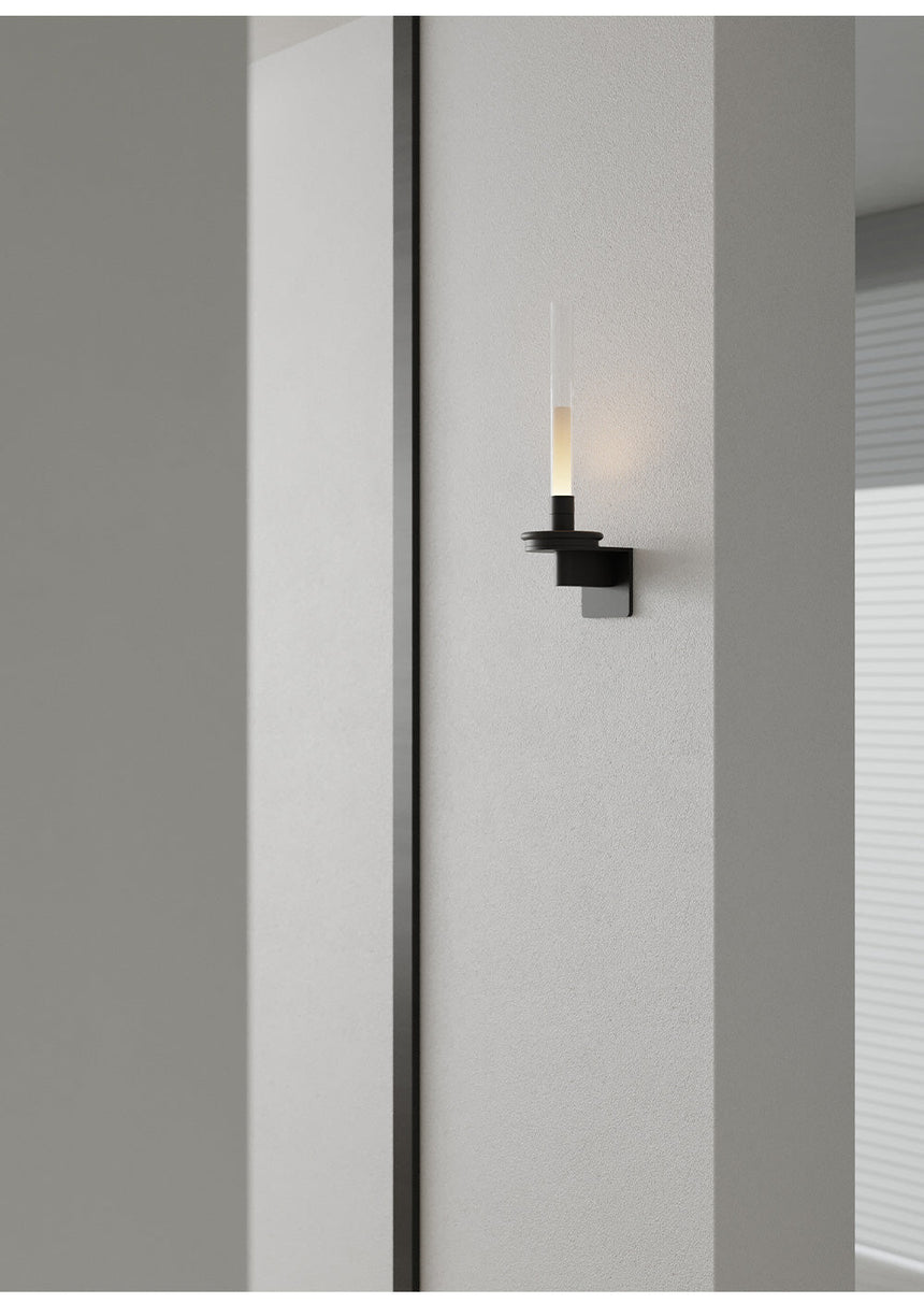Lit on a gray corridor wall beside a tall dark panel running floor to ceiling