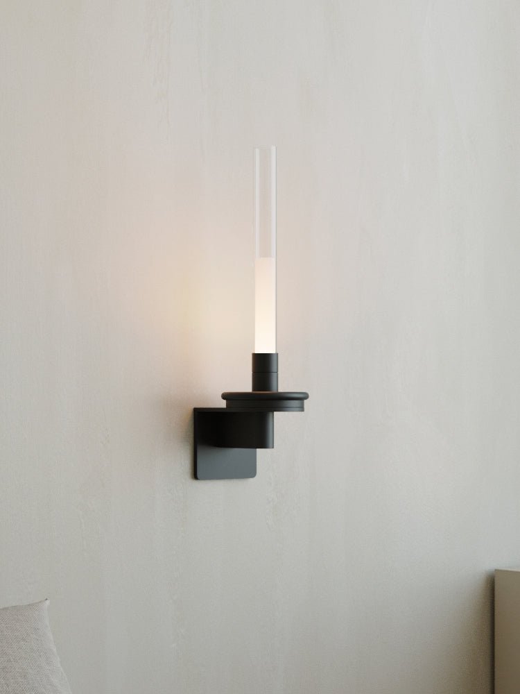 Lit warm on a pale wall, the stem glowing above its black stepped bracket