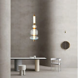 The stacked bead pendant lit above a round dining table beside a chair