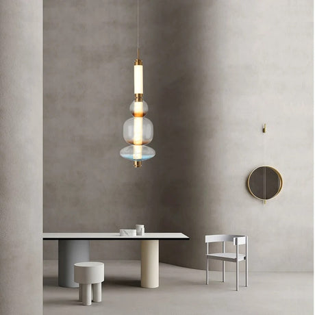 The stacked bead pendant lit above a round dining table beside a chair