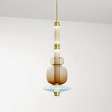The stacked glass bead pendant lit against a pale wall above a shelf