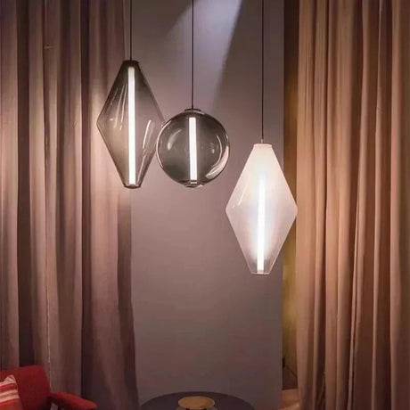 A diamond and two sphere pendants lit in front of a long curtain beside a chair