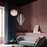 Three glass pendants, two spheres and one diamond, lit in a living room with a sofa