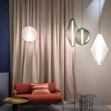 Three glass pendants hung at different heights against a pale pink wall