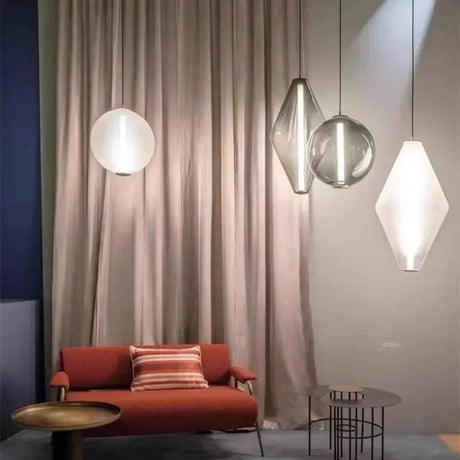 Three glass pendants hung at different heights against a pale pink wall