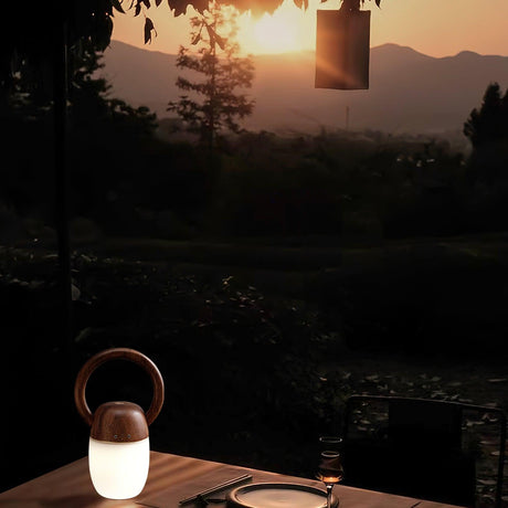 Dimmable bedside lamp lit on a table at dusk with hills behind