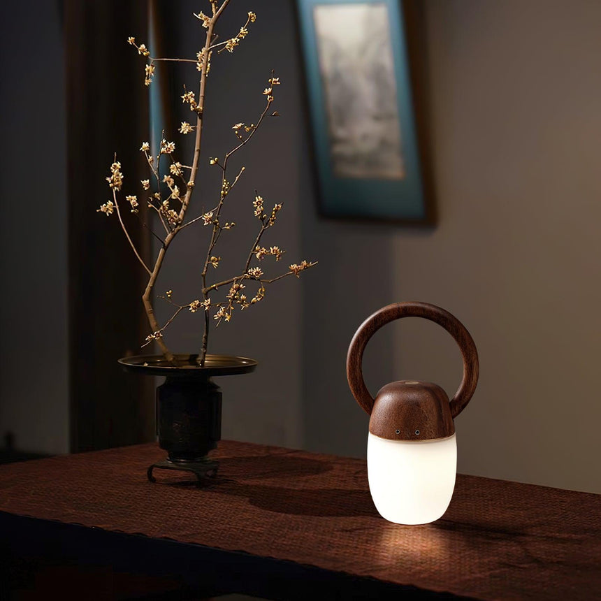 Dimmable bedside lamp lit on a dark table below a framed picture