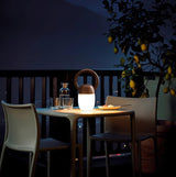 Dimmable bedside lamp lit on a terrace table under a lemon tree