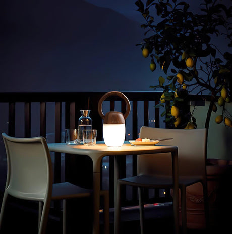 Dimmable bedside lamp lit on a terrace table under a lemon tree