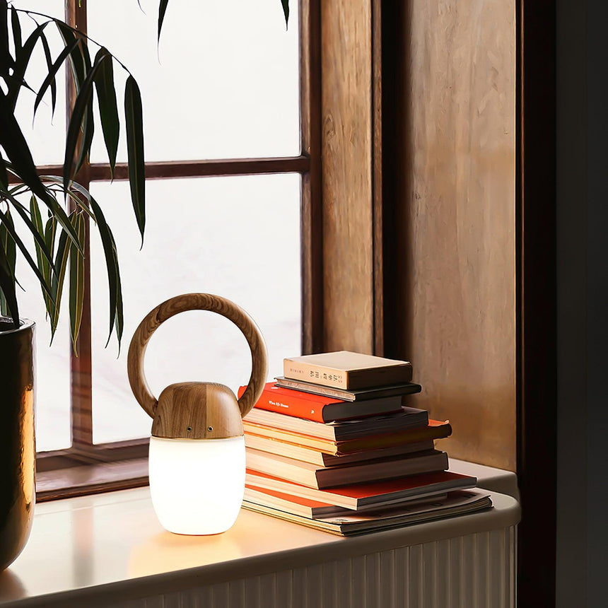 Dimmable bedside lamp lit on a window ledge beside a stack of books