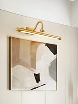 Brass bar seen from the side, lit above a framed canvas in a corner
