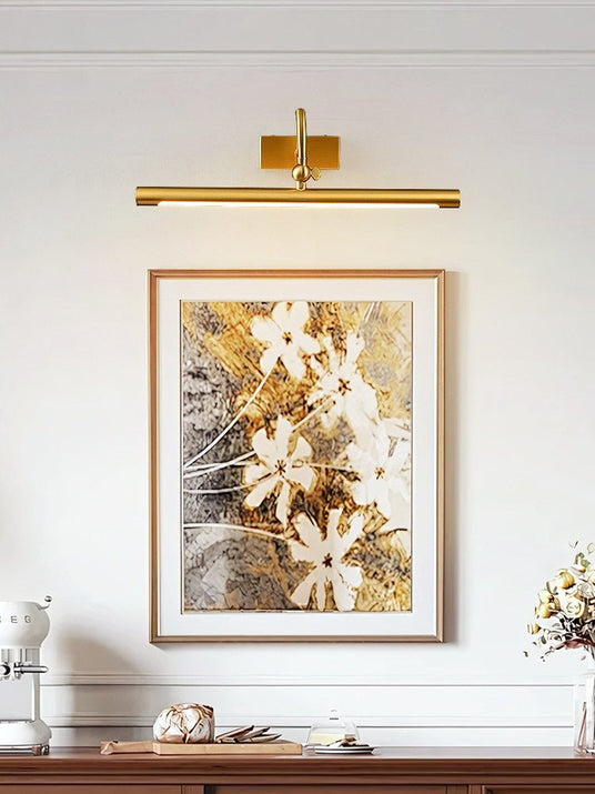 Brass bar lit over a framed floral canvas above a console with white objects