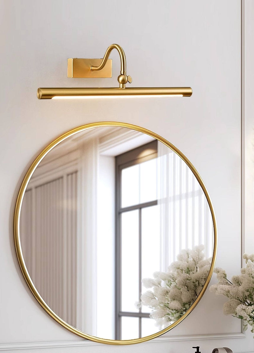 Brass bar lit above a round mirror reflecting a bright window and a curtain