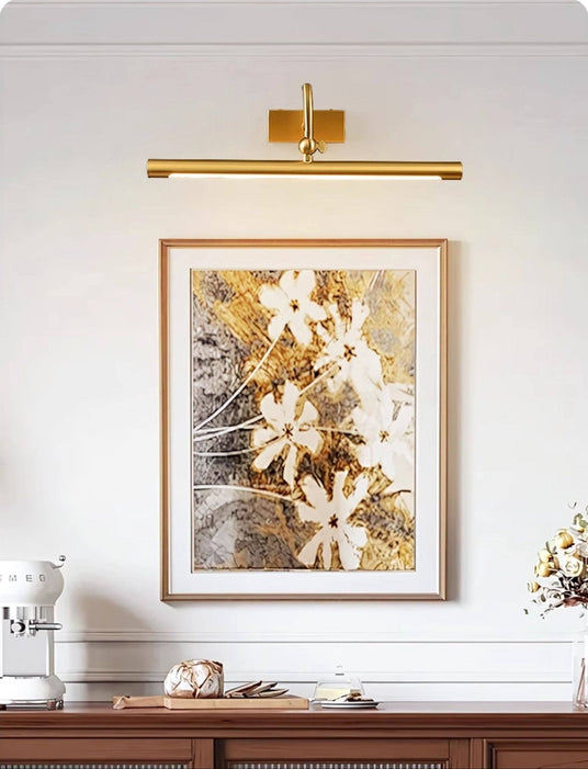 Brass bar lit over a framed canvas above a dark wood console with vases