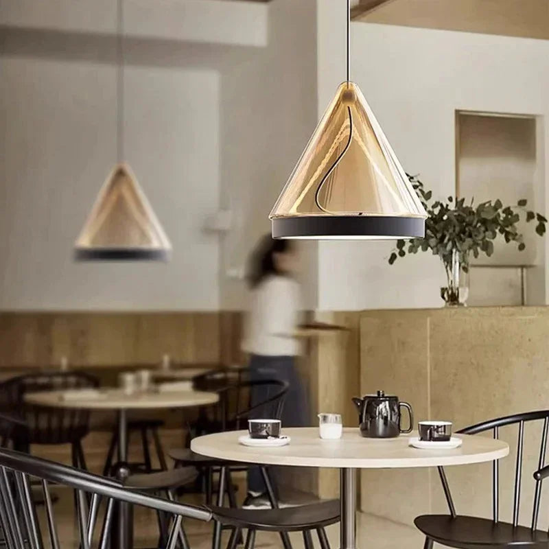 Two amber cone pendants lit above a round dining table with pale chairs