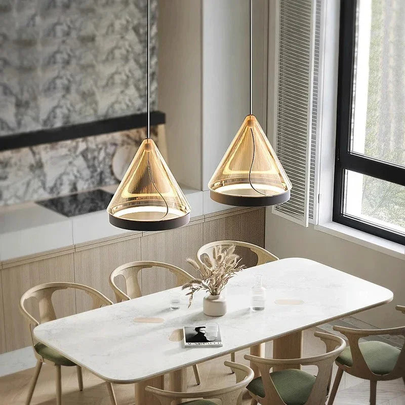 Two cone pendants lit above a marble dining table with wooden chairs