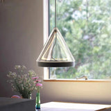A cone pendant lit beside a window with flowers on the sill