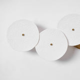 Three textured ceramic discs unlit on a white wall