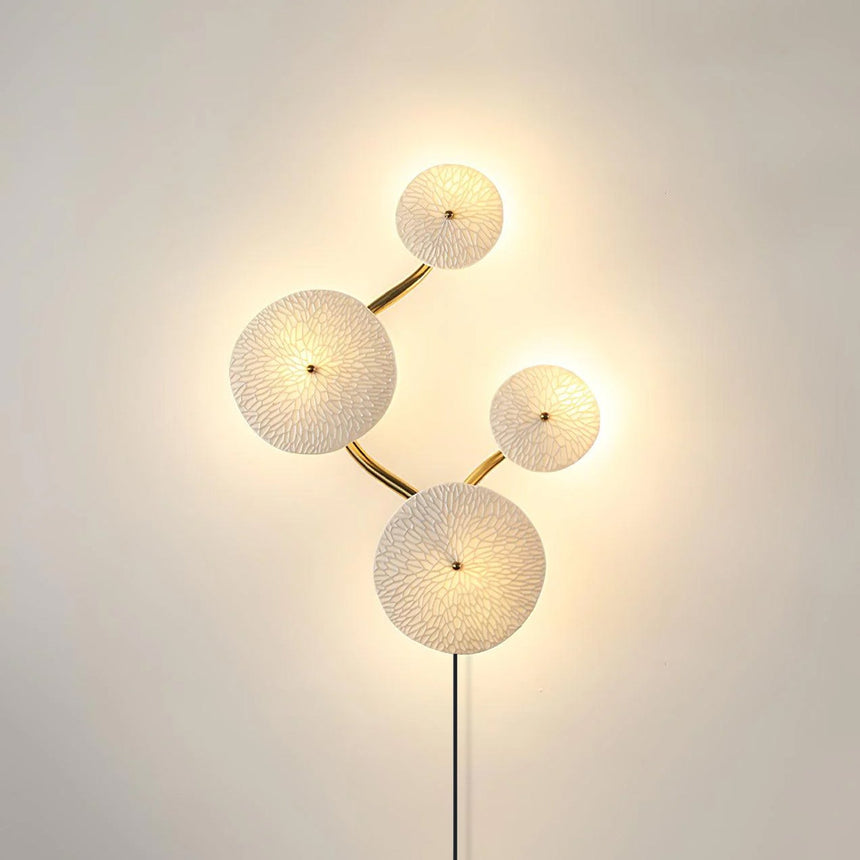 Four discs lit on a curving stem, the light pooling around each edge