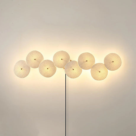 Eight discs in a long horizontal row glowing on a warm wall