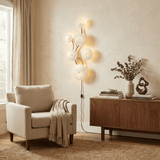 The vertical version lit beside a cream armchair, its cord running to the floor