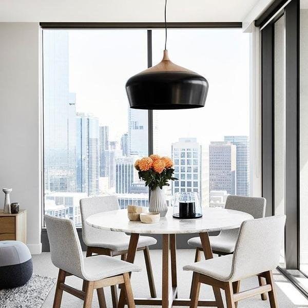 Black dome hung above a dining table by a window