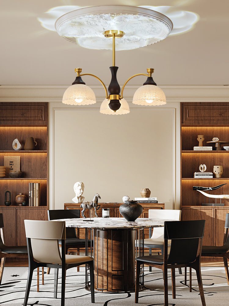 Chandelier lit in a dining room beside shelves and a round table