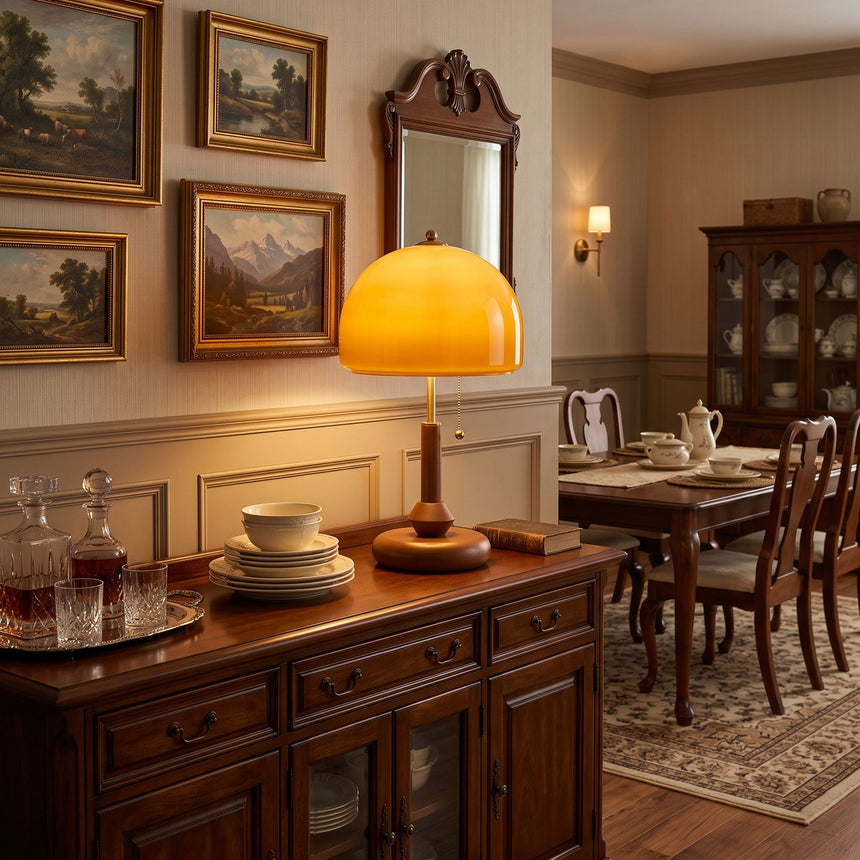 Amber dome table lamp lit on a sideboard in a dining room with pictures