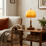 Amber dome table lamp lit on a side table beside a pale armchair
