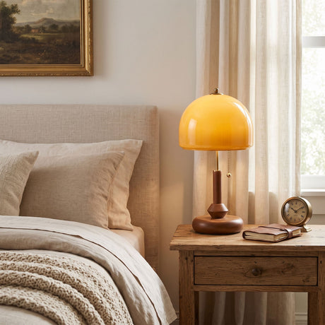 Amber dome table lamp lit on a nightstand in a pale bedroom