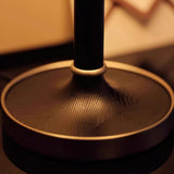 Close view of the brushed brass disc foot under the dark stem