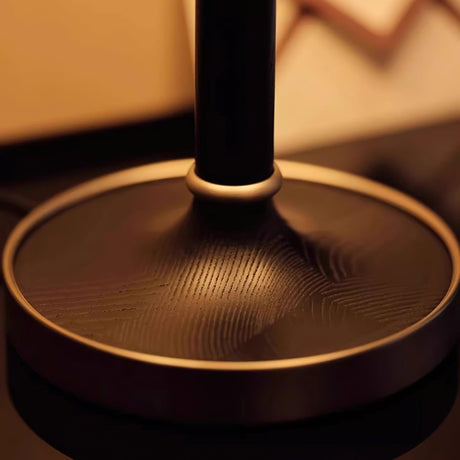 Close view of the brushed brass disc foot under the dark stem