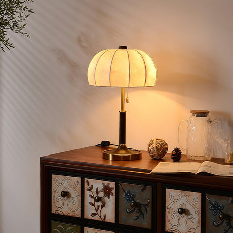 Segmented dome lamp lit on a console in a room with pale walls