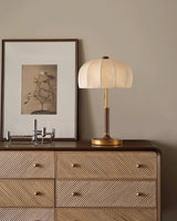Segmented dome lamp lit on a cane fronted dresser below a print