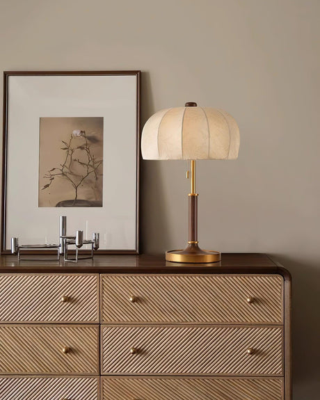 Segmented dome lamp lit on a cane fronted dresser below a print
