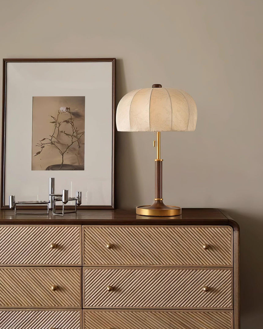 Segmented dome lamp lit on a cane fronted dresser below a print
