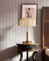 Segmented dome lamp lit on a small dark side table by a patterned wall