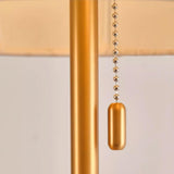 Close view of the beaded pull chain hanging beside the brass stem
