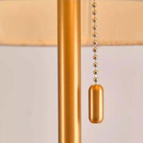Close view of the beaded pull chain hanging beside the brass stem