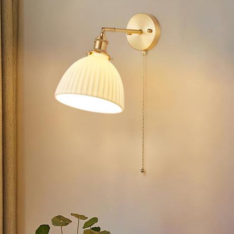 The dome shade lit warm on a beige wall, the pleats glowing