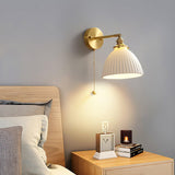 The dome sconce lit above a wood nightstand with a clock and a candle beside a bed