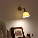 The sconce lit above a lace covered table with a framed picture and a copper kettle