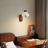 Sconce lit beside a bed above a small desk with a framed picture on it