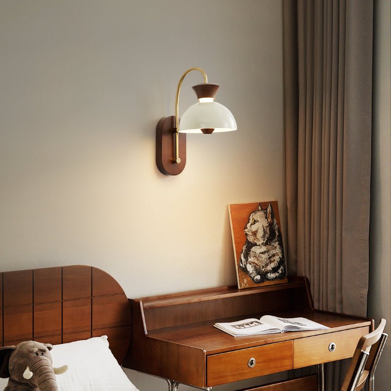 Sconce lit beside a bed above a small desk with a framed picture on it