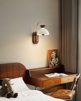 Sconce lit above a desk beside a bed, an open book lying on the surface