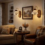 Two sconces lit either side of framed artwork above a sofa and a side table